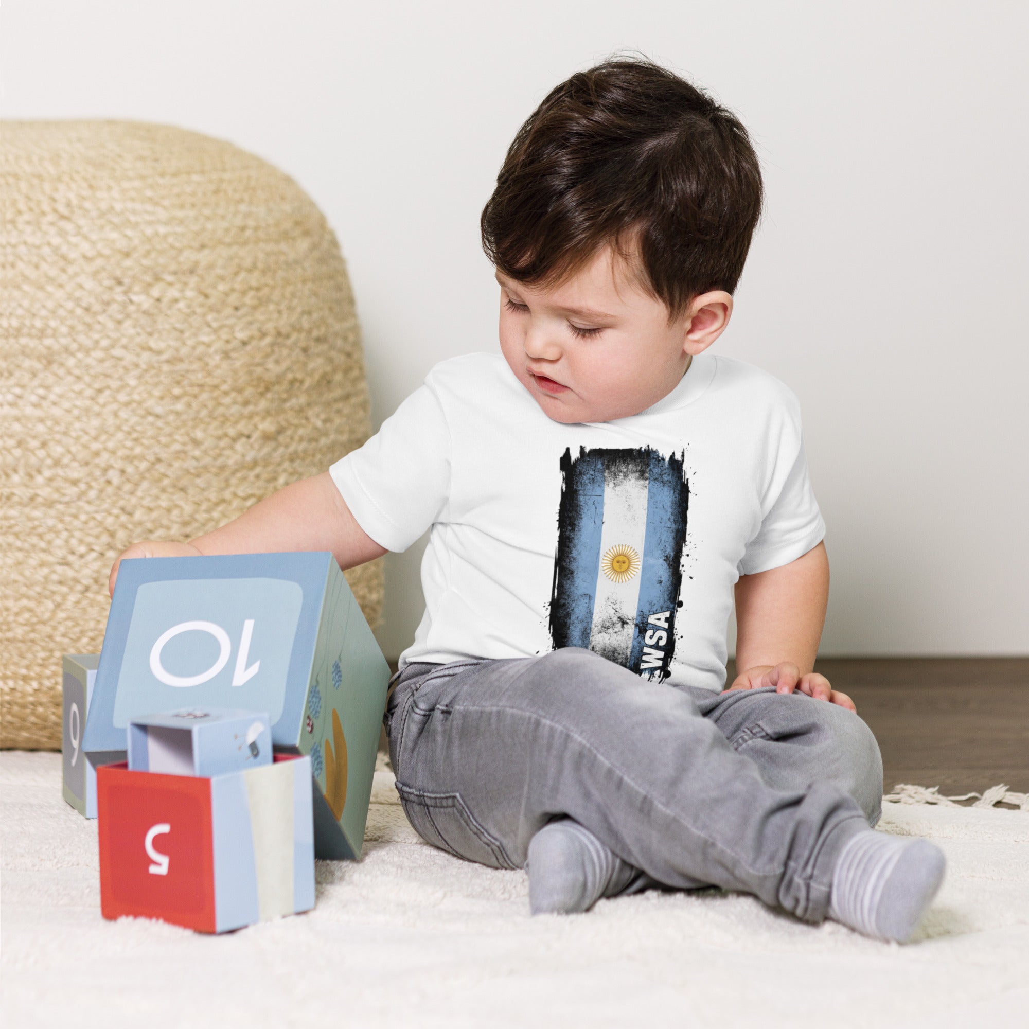 Child sitting on a carpeted floor with a colorful toy and a book titled 'WSA'.