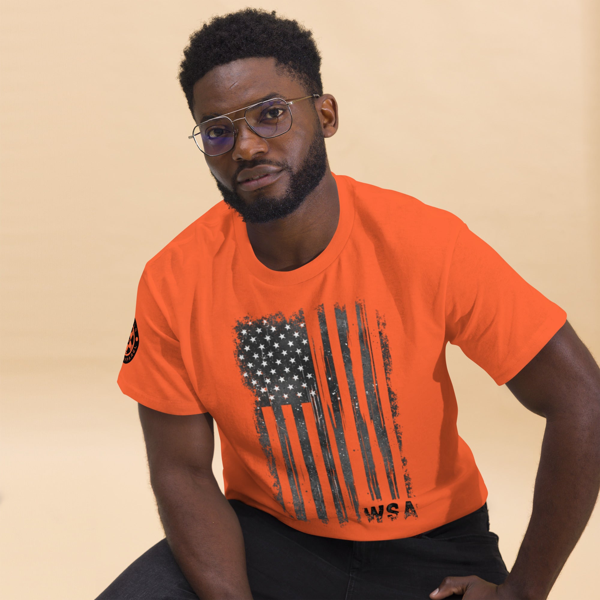 Man wearing an orange t-shirt with a graphic design on a beige background