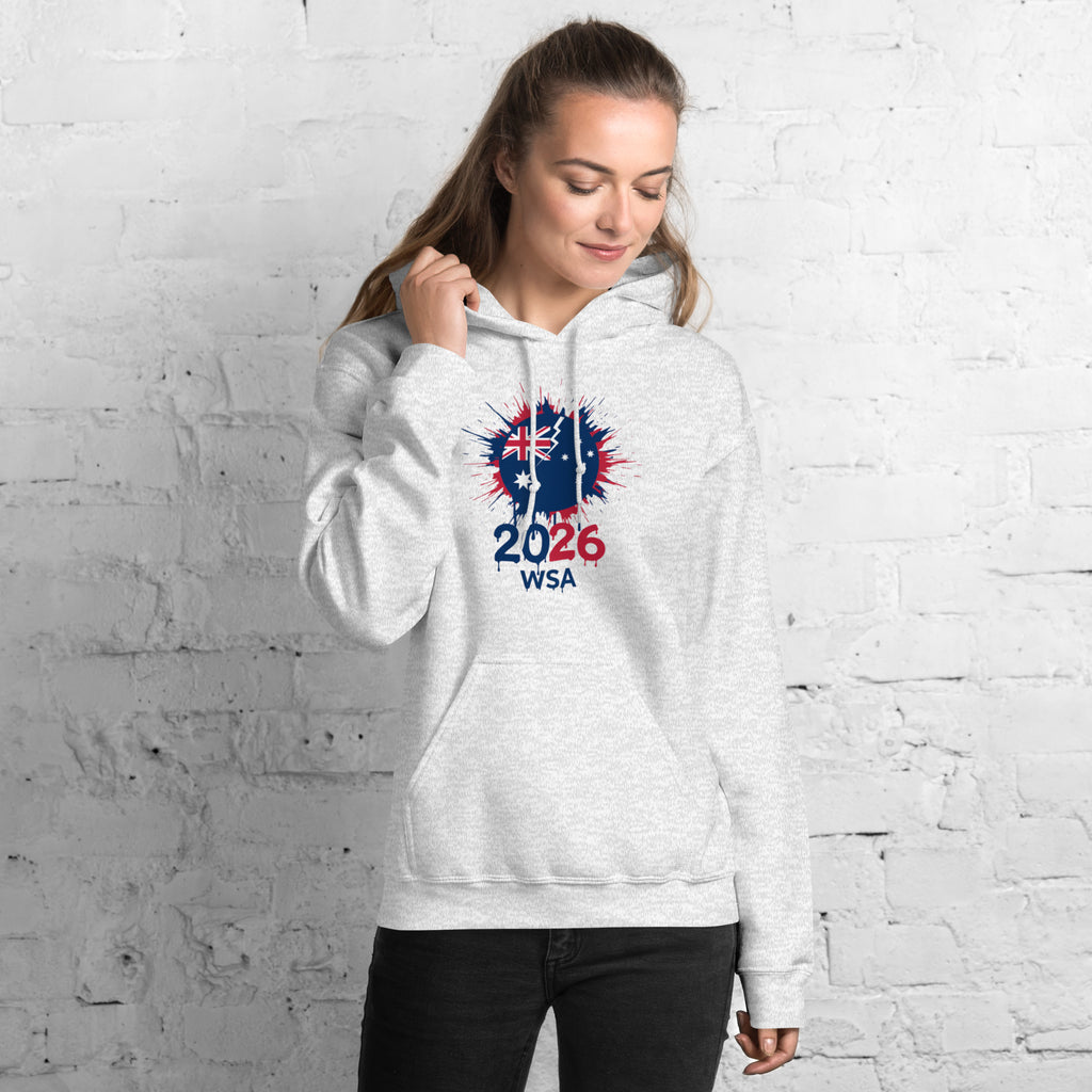 Woman wearing a white hoodie with a design and text against a white brick wall.