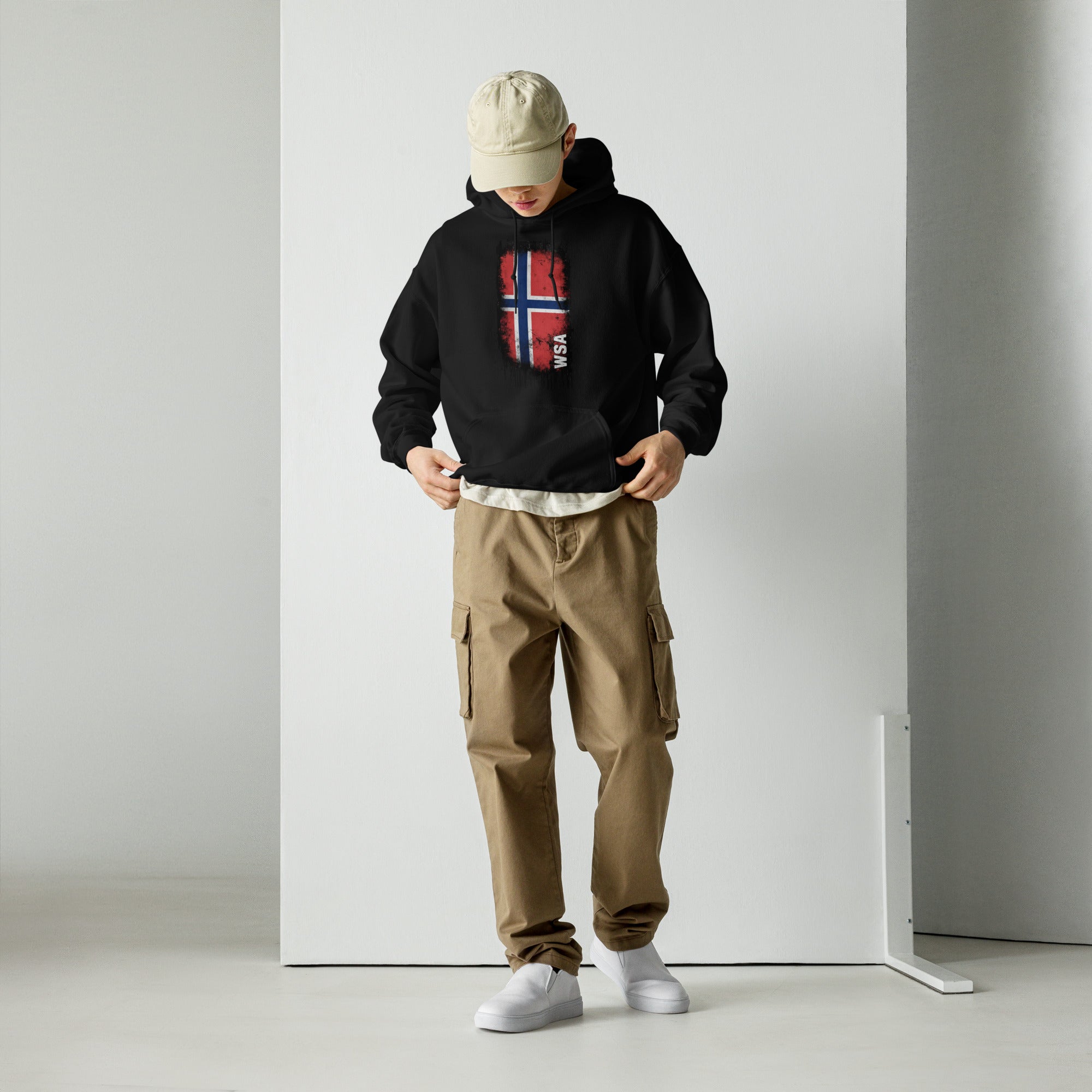 Person wearing a black hoodie with 'SLONVE' text, beige cap, and cargo pants against a white background