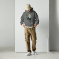Person wearing a gray hoodie with a colorful design and '2026' text, brown cargo pants, and white shoes on a plain background.