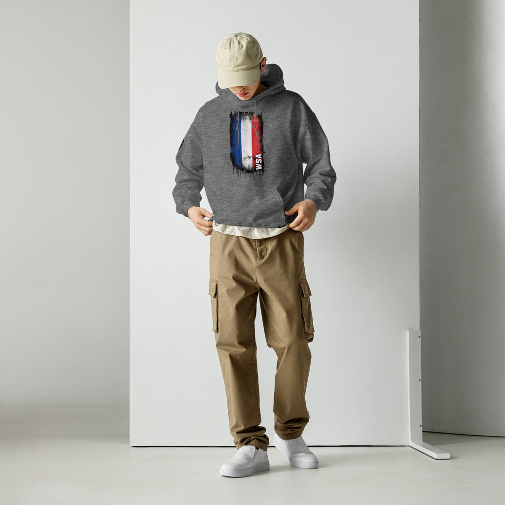 Person wearing a gray hoodie with text and brown cargo pants standing against a white wall.