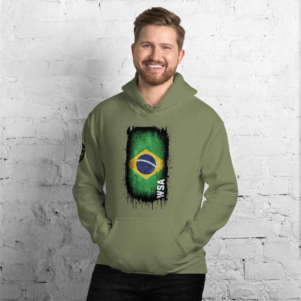 Man wearing a green hoodie with a flag design against a white brick wall.