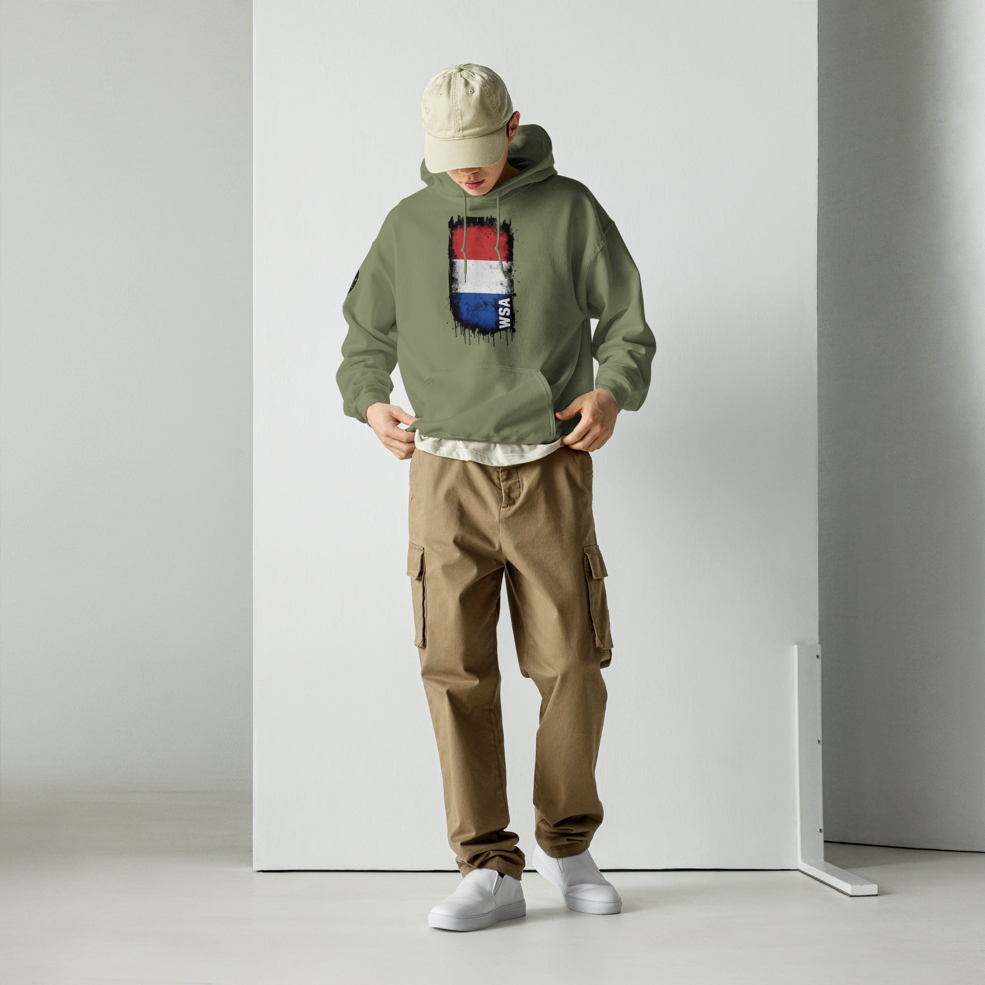 Person wearing a green hoodie with a colorful patch and brown cargo pants against a white background