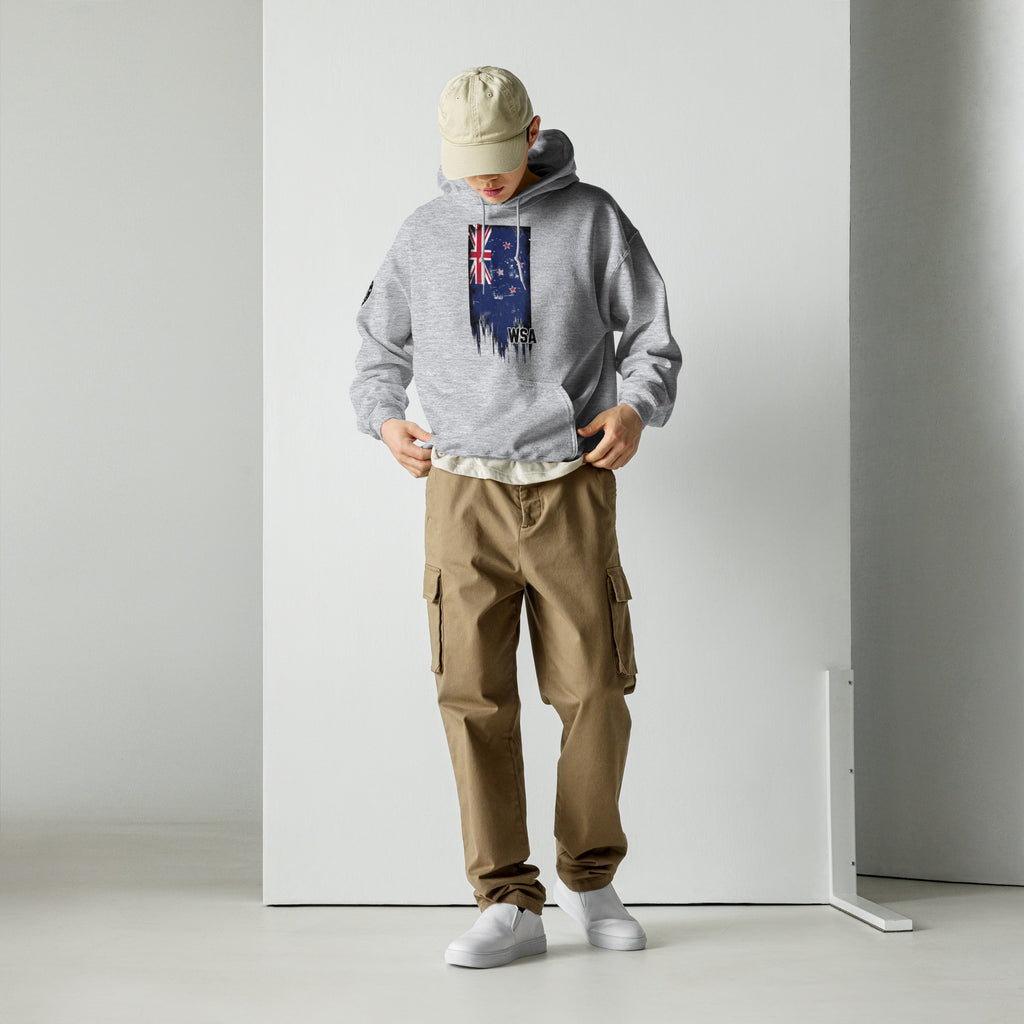 Person wearing a gray hoodie with a flag design, beige cap, and brown cargo pants against a white background.