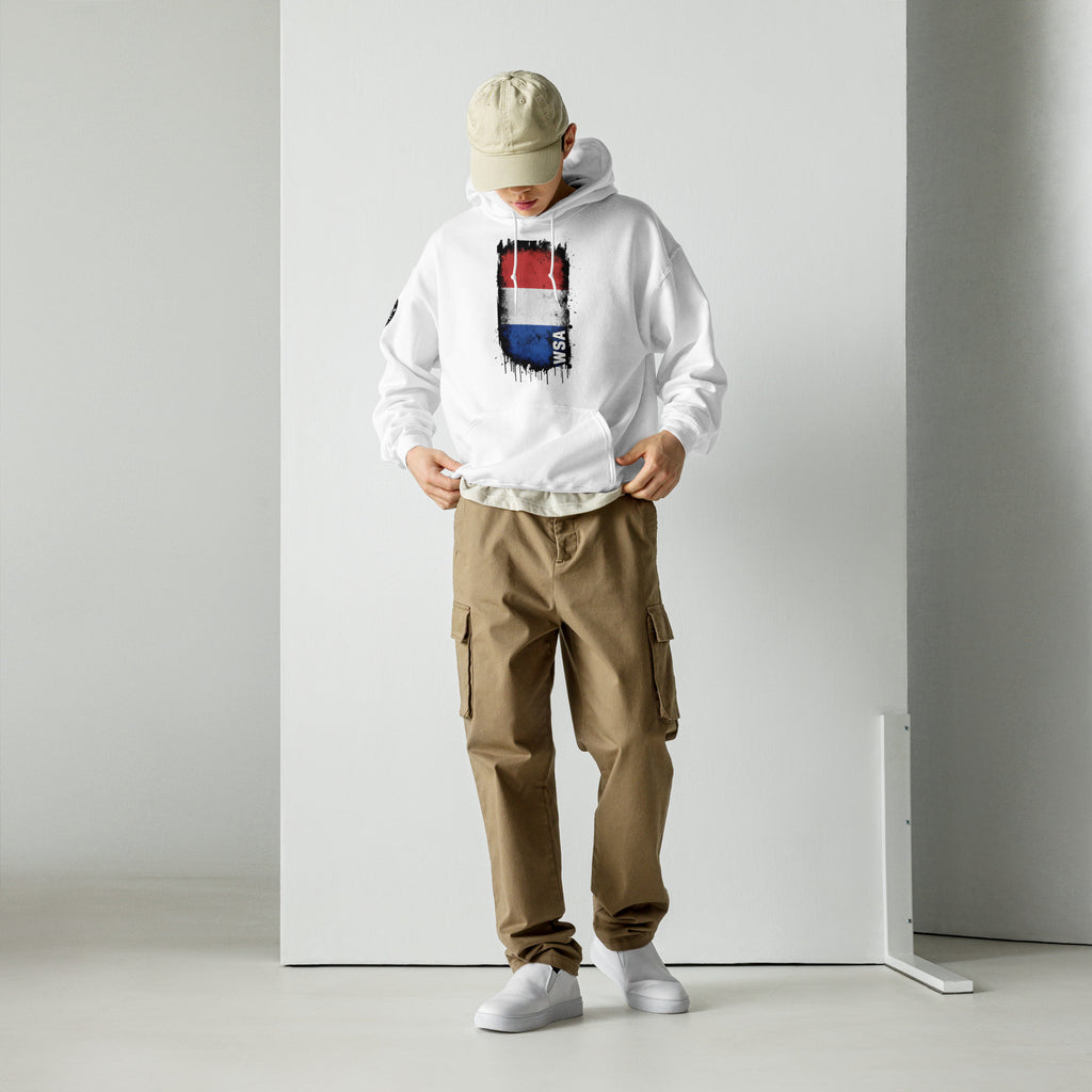 Person wearing a white hoodie with a graphic design, beige cap, brown cargo pants, and white sneakers on a plain background.