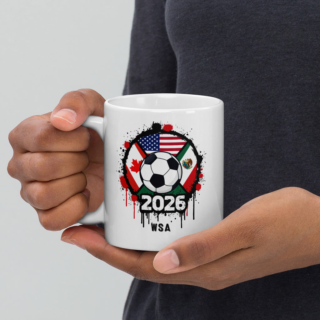 Person holding a white mug with a soccer-themed design featuring flags and '2026 WSA' text.