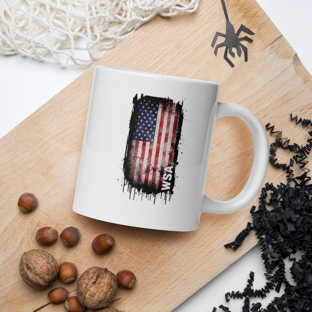 White mug with American flag design on a wooden board with nuts and decorative elements.